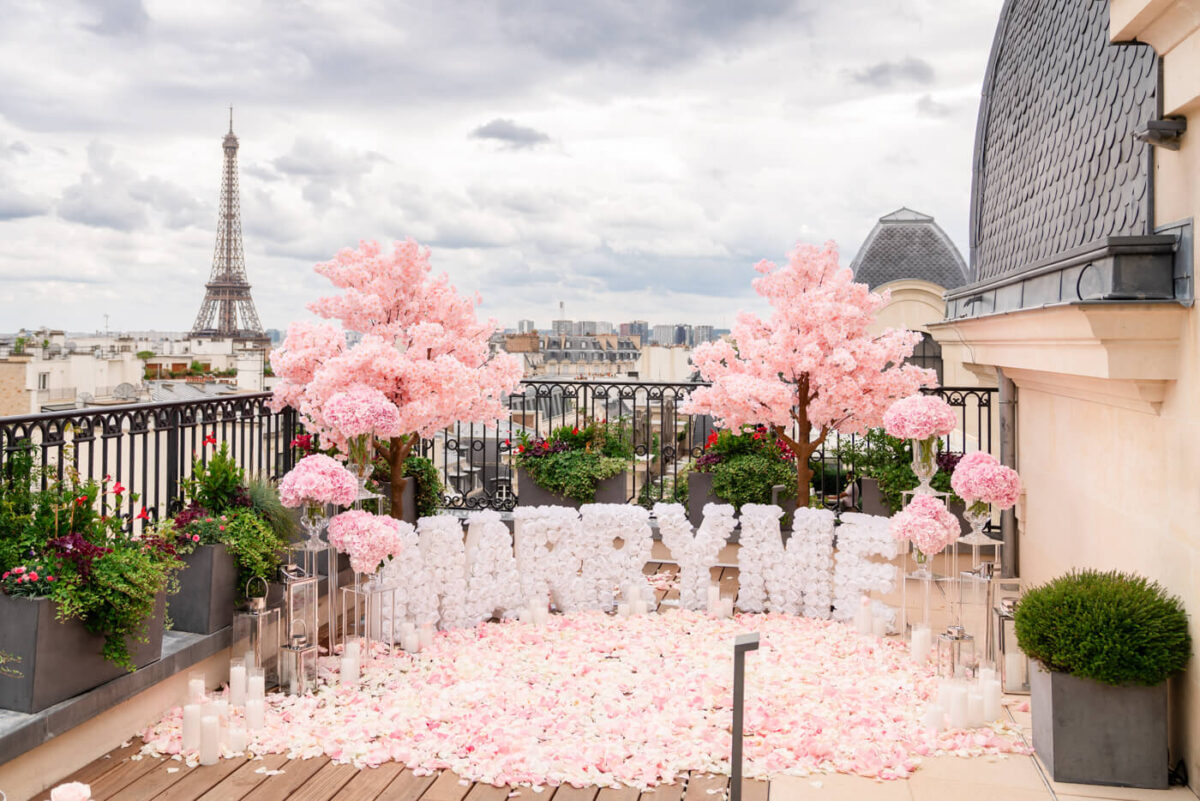 Romantic cherry blossom proposal in Paris with "Marry Me" letters and Eiffel Tower view