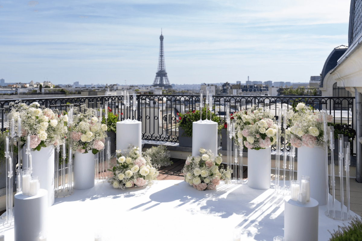 Eternal Elegance setup at Peninsula Hotel with white carpet, floral arrangements on column pedestals, and glowing candelabras and hurricane candle holders.