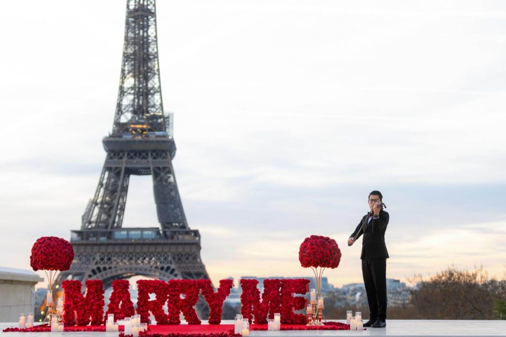 Red 'Marry Me' setup at sunrise on Trocadéro with a master musician and stunning Eiffel Tower view, perfect for a romantic Paris proposal.